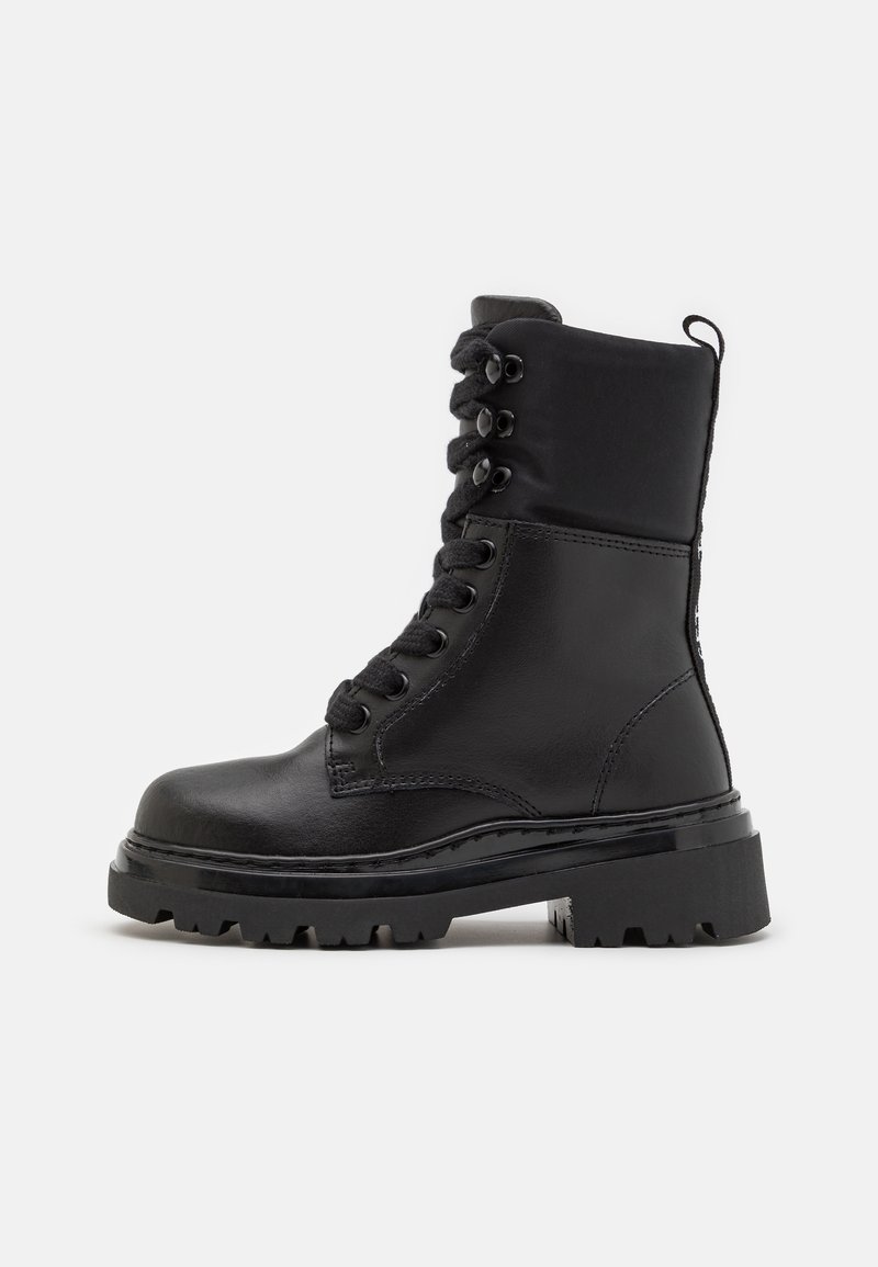 Botte de combat noire en cuir à lacets avec semelle épaisse et robuste et col rembourré à la cheville sur fond blanc.