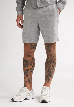 Stribede shorts i lysegråt og hvidt stof med skræddersyet pasform og sidelommer, kombineret med hvide sneakers.