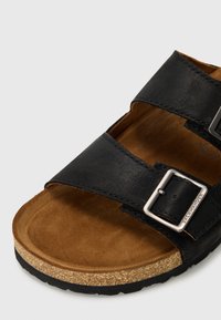 Fekete bőrszandál, két állítható pánttal, ezüst hardware-ral és barna velúr talppal. Parafa talp, textúrált fekete gumitalppal.
