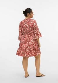Robe à motifs rouge et crème avec un ourlet évasé et des manches en cloche, dotée d'une taille à nouer et d'une coupe ample, fabriquée en tissu léger.