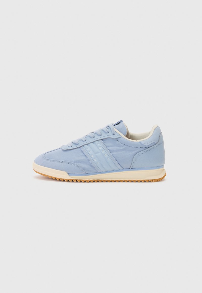 Lyseblå sneakers med overdel i lær, teksturerte paneler, tre hvite striper og såle i gummi. Rund tå og snøring.
