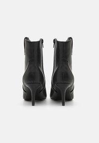 Bottes à cheville en cuir noir avec un talon haut, équipées de fermetures éclair sur les côtés et d'une texture lisse, conçues avec un dos pointu.