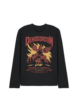 Black long-sleeve shirt with red and yellow Demogorgon creature graphic, flames backdrop, and event text referencing Hawkins, Indiana, November 6th.