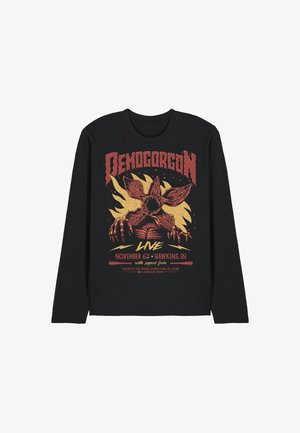 Black long-sleeve shirt with red and yellow Demogorgon creature graphic, flames backdrop, and event text referencing Hawkins, Indiana, November 6th.