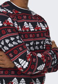 Maglione a maglia con un motivo festivo che presenta camion rossi, alberi bianchi e fiocchi di neve su uno sfondo blu navy. Collo e polsini a coste.