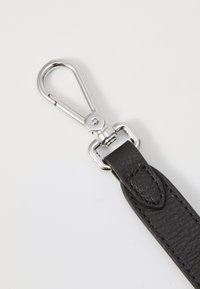 Bracelet en cuir noir avec une finition texturée et un fermoir en métal argenté. Le fermoir est conçu avec un mécanisme à ressort pour un attachement facile.