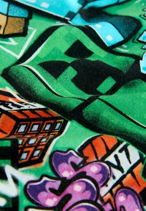 Colorful fabric with a vibrant green background featuring graphic patterns, including houses, a basketball, and stylized text in purple and orange.