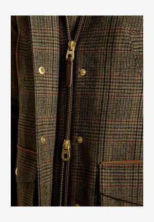 Brown checked jacket made of textured fabric featuring a gold zipper, brown leather accents, and brass snap buttons.