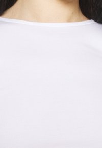 Weißes Baumwoll-T-Shirt mit rundem Halsausschnitt und kurzen Ärmeln. Der Stoff hat eine glatte Textur mit einem leichten Glanz.