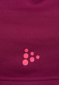 Magenta träningsmaterial har en texturerad yta med en rosa cirkulär logotypdesign i det nedre högra hörnet. Kanterna är sydda för hållbarhet.