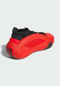 Zapatilla roja y negra con una suela redondeada texturizada, acentos de malla y una lengüeta para tirar. Material superior suave con elementos de diseño en capas.