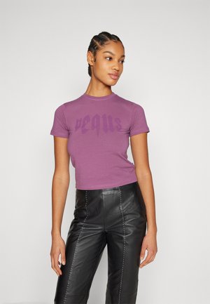 T-shirt court violet à manches courtes et col rond, orné de texte violet foncé sur le devant, associé à un pantalon en cuir noir taille haute.