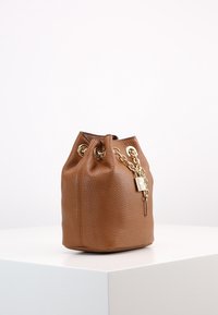 Sac seau en cuir brun avec une surface texturée, des accessoires en or, un détail en chaîne, une fermeture à cordon, et un accent de cadenas.