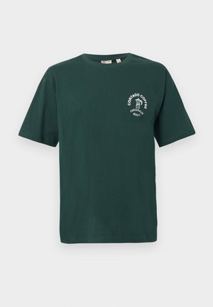 Grünes Baumwoll-T-Shirt mit kurzen Ärmeln, Rundhalsausschnitt und einem weißen "Cortado Coffee"-Logo mit einer Kaffeetasse-Grafik auf der Brust.