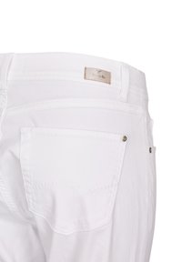 White jeans featuring a classic design with five pockets, detailed stitching, and a branded leather patch at the waistband.