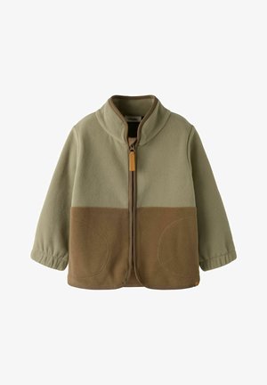 Két tónusú polárdzseki bézs és barna színekben, teljes elülső cipzárral, magas gallérral, rugalmas mandzsettákkal és lekerekített elülső zsebekkel.