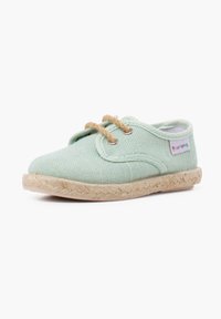 Scarpa in tela verde menta con punta rotonda, lacci in corda e suola in juta intrecciata. Presenta occhielli e dettagli cuciti lungo i bordi.