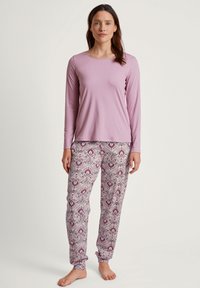 Helllila Langarmoberteil, kombiniert mit gemusterten Hosen mit Paisleymuster in verschiedenen Lila- und Weißtönen. Weiches, bequemes Material.