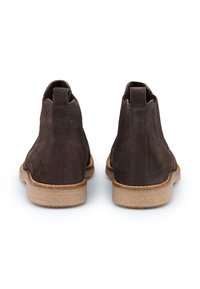 Brune ruskind ankle støvler med en lav, tekstureret korksål, der har et enkelt design og to trækflapper på bagsiden for nem påklædning.