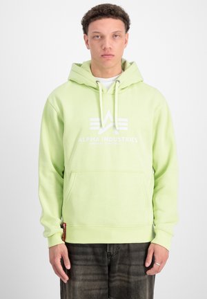 Svetlozelená mikina s kapucňou a predným vreckom, s bielym logom "ALPHA INDUSTRIES" a dekoračnými detailmi.