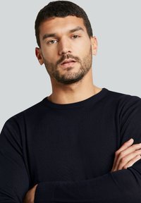 Marineblauer Rundhalspullover aus geripptem Stoff mit langen Ärmeln, schlanker Schnittführung und strukturierten Oberflächendetails.