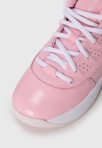 Zapato deportivo rosa con acabado brillante, cordones blancos, detalles perforados y una suela blanca texturizada.