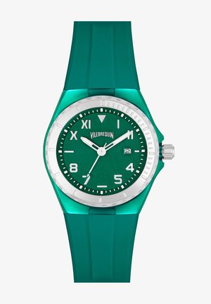Reloj de pulsera de silicona verde con una esfera texturizada en verde, bisel plateado y marcadores de horas blancos. Presenta una pantalla de fecha y forma de caja redonda.
