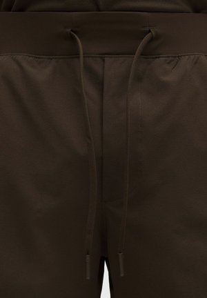 Pantaloncini sportivi marroni con vita a coulisse, caratterizzati da una texture liscia e dettagli di cuciture minimi. Adatti per l'abbigliamento sportivo.
