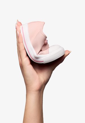 Zapatilla rosa con un upper texturizado, suela de goma y acentos blancos. Mano sosteniendo la zapatilla, mostrando su diseño flexible.