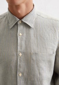 Gestreiftes Hemd in Hellblau und Weiß. Verfügt über einen Button-Down-Kragen, eine Brusttasche und beigen Knöpfen mit einer strukturierten Stoffoberfläche.