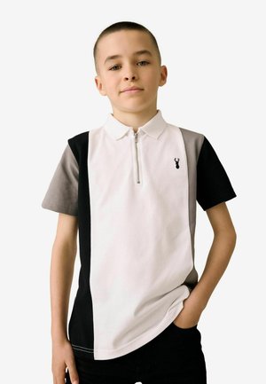 Polo à manches courtes en blanc, gris et noir, avec un col zippé et un design à panneau latéral. Présente un petit logo noir sur la poitrine.