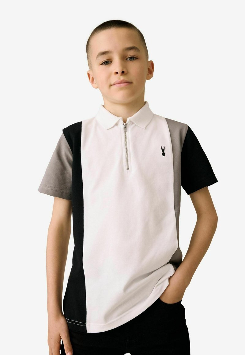 Polo à manches courtes en blanc, gris et noir, avec un col zippé et un design à panneau latéral. Présente un petit logo noir sur la poitrine.