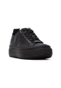 Zapatilla negra de cuero con suela de goma gruesa, punta redonda, diseño de cordones y una suela texturizada negra. Presenta un detalle de marca en naranja en la lengüeta.