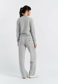 Grijze loungewear set met een trui met ronde hals en wijde broek. Opmerkelijke details zijn een Hello Kitty-patch op de achterzak.
