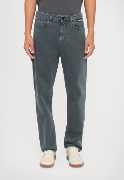 Mørkegrå jeans med lige ben-design, lavet af bomulds materiale, fem lommer og knaplukning. Båret med hvide sneakers.