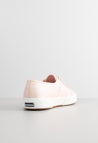 Sneaker in tela rosa chiaro con suola in gomma bianca, tomaia testurizzata e cinque occhielli. Logo "SUPERGA" in bianco e nero sul tallone.