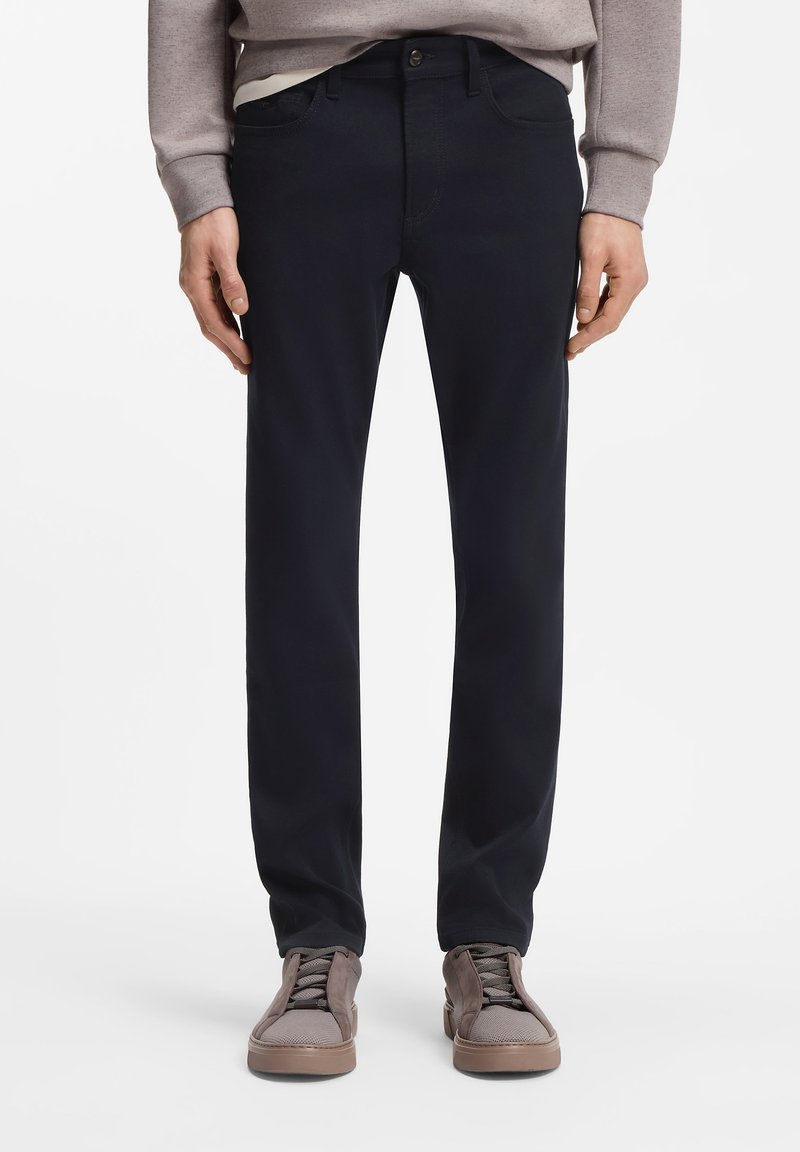 Μπλε ναυτικό παντελόνι από βαμβακερό μείγμα με ίσια γραμμή, διαθέτει μπροστινές τσέπες και κλείσιμο με κουμπί, συνδυασμένο με καφέ αθλητικά παπούτσια.