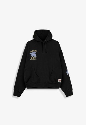 Sudadera negra con capucha, bolsillo tipo canguro en la parte delantera, gráfico de una pequeña criatura alada y texto en el pecho, detalle de estrella en la manga derecha, capucha con cordón ajustable.