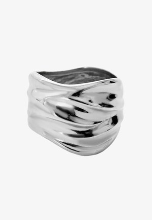 Anillo de metal plateado con un diseño ondulado y texturizado y un acabado suave. Presenta una forma amplia, estrechándose en los extremos, destacando una artesanía única.