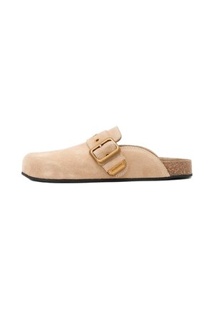 Sabot beige en daim à enfiler avec une grande boucle dorée réglable et une semelle en liège, conçu pour un usage décontracté.
