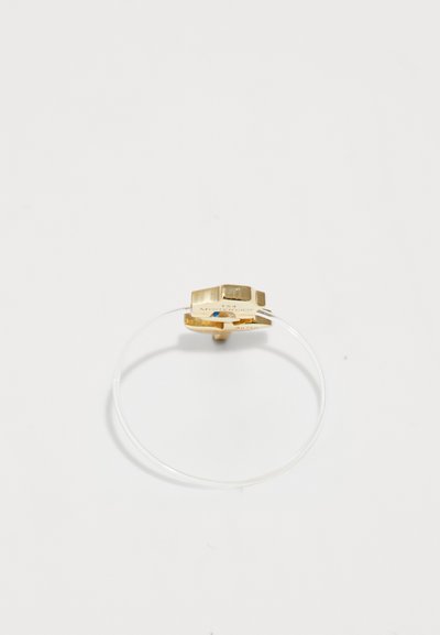 Anello in metallo dorato con una fascia trasparente. Presenta un design geometrico con una finitura liscia e dettagli incisi sulla superficie interna.