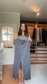 Gray, knee-length skirt with a front slit, elastic waistband and a front button detail. Fabric appears smooth and lightweight.