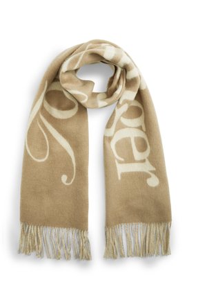 Beige uldhalv med store hvide skriftbogstaver og frynser i enderne, foldet i en løkke og lagt fladt på en hvid baggrund.