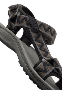 Brune og svarte mønstrede sandaler med justerbare stropper, gummisåle og teksturert fotseng, med spenne og logodetalj.