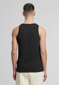Sort bomulds tanktop med rund hals og standard pasform, med brede ærmegab. Glat tekstur med et rent, enkelt design.