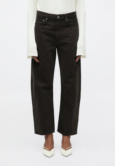 Jean large marron foncé avec taille haute, comportant une fermeture à bouton, cinq poches et de subtils détails usés au niveau des genoux.