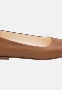 Scarpa flat in pelle marrone con punta arrotondata e profilo basso. Texture liscia con un design semplice e dettagli di cucitura minimi.