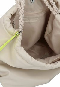 Sac à main beige clair avec des poignées en tressé, un extérieur lisse et une poche intérieure zippée. Présente un accent jaune fluo et un matériau doux et texturé.