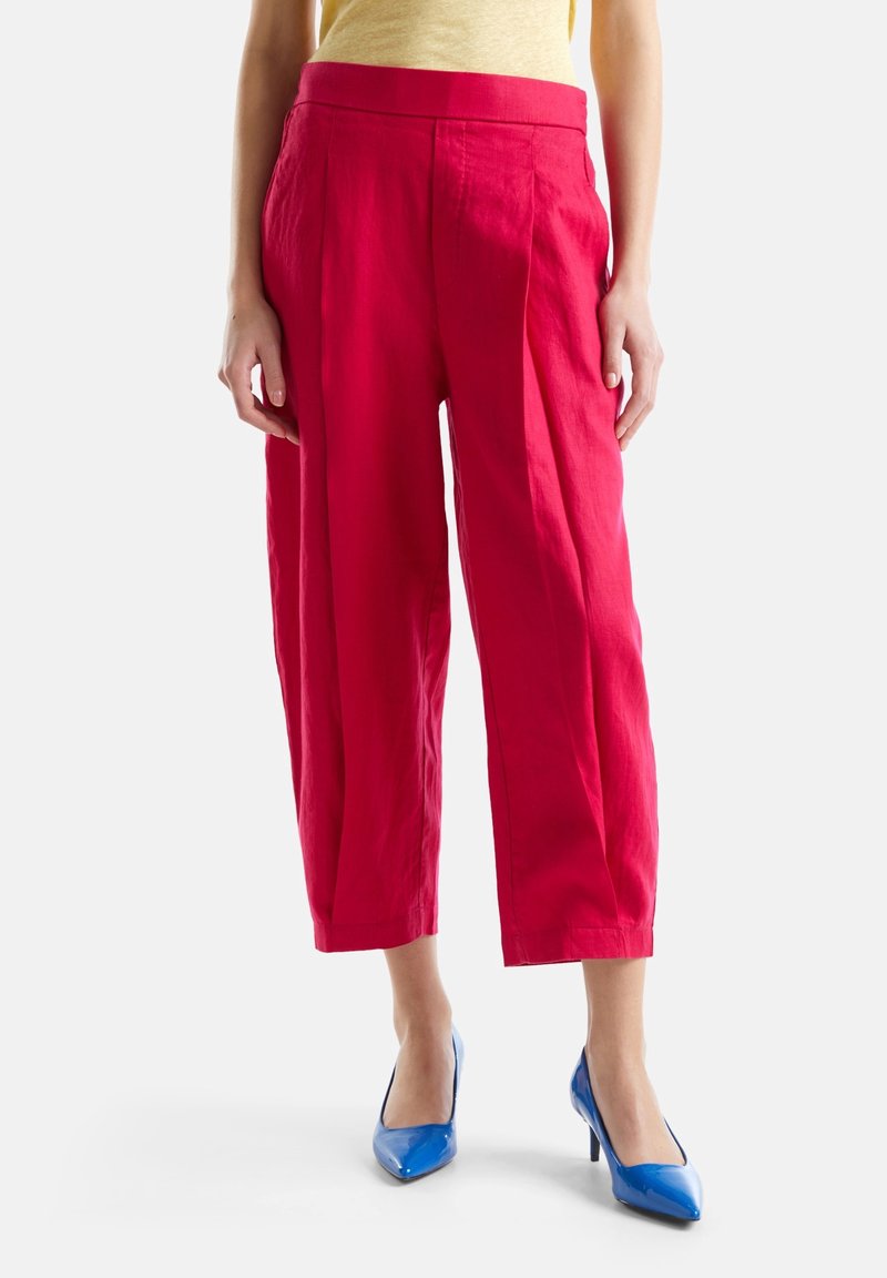 Rote Leinen-Culotte mit weiter Beinform, hoch tailliert und mit Faltendetails. Kombiniert mit blauen High Heels.