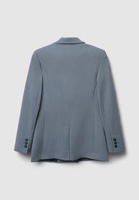 Blazer grigio con una texture liscia, revers a notched, spacco singolo e tre bottoni neri su ciascun maniche. Design semplice e sartoriale.